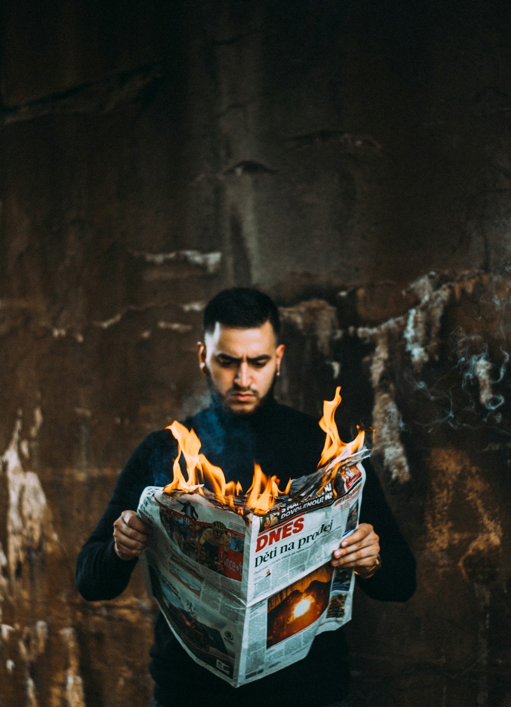 man holding burning newspaper