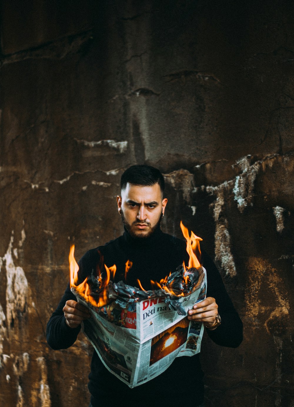man holding flaming newspapeer