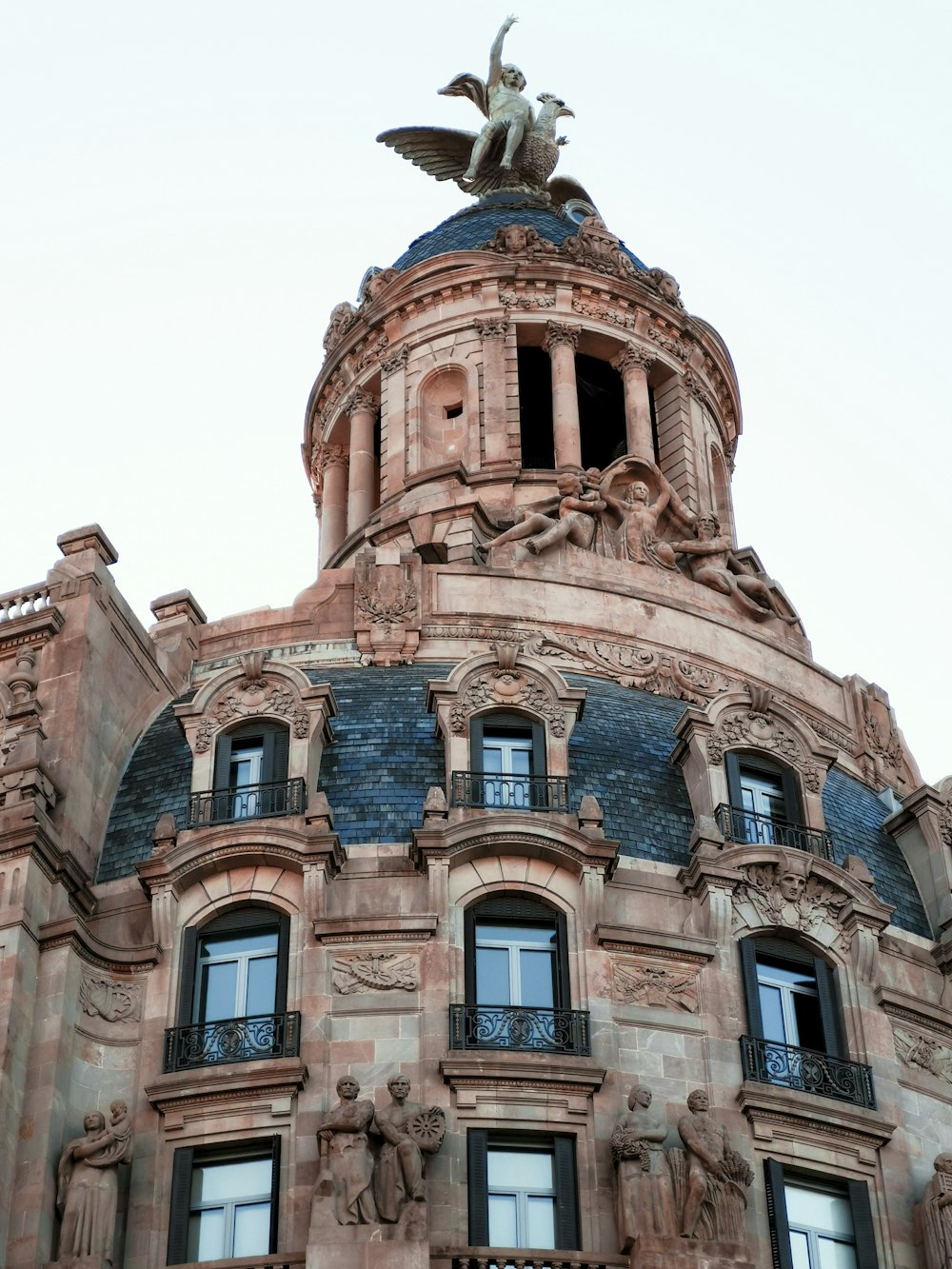 winged human figure statue on top of building