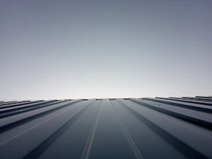A freshly installed modern black and gold pitched roof gleaming under a clear sky.