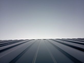 A freshly installed black roof gleaming under a clear blue sky on a modern home.