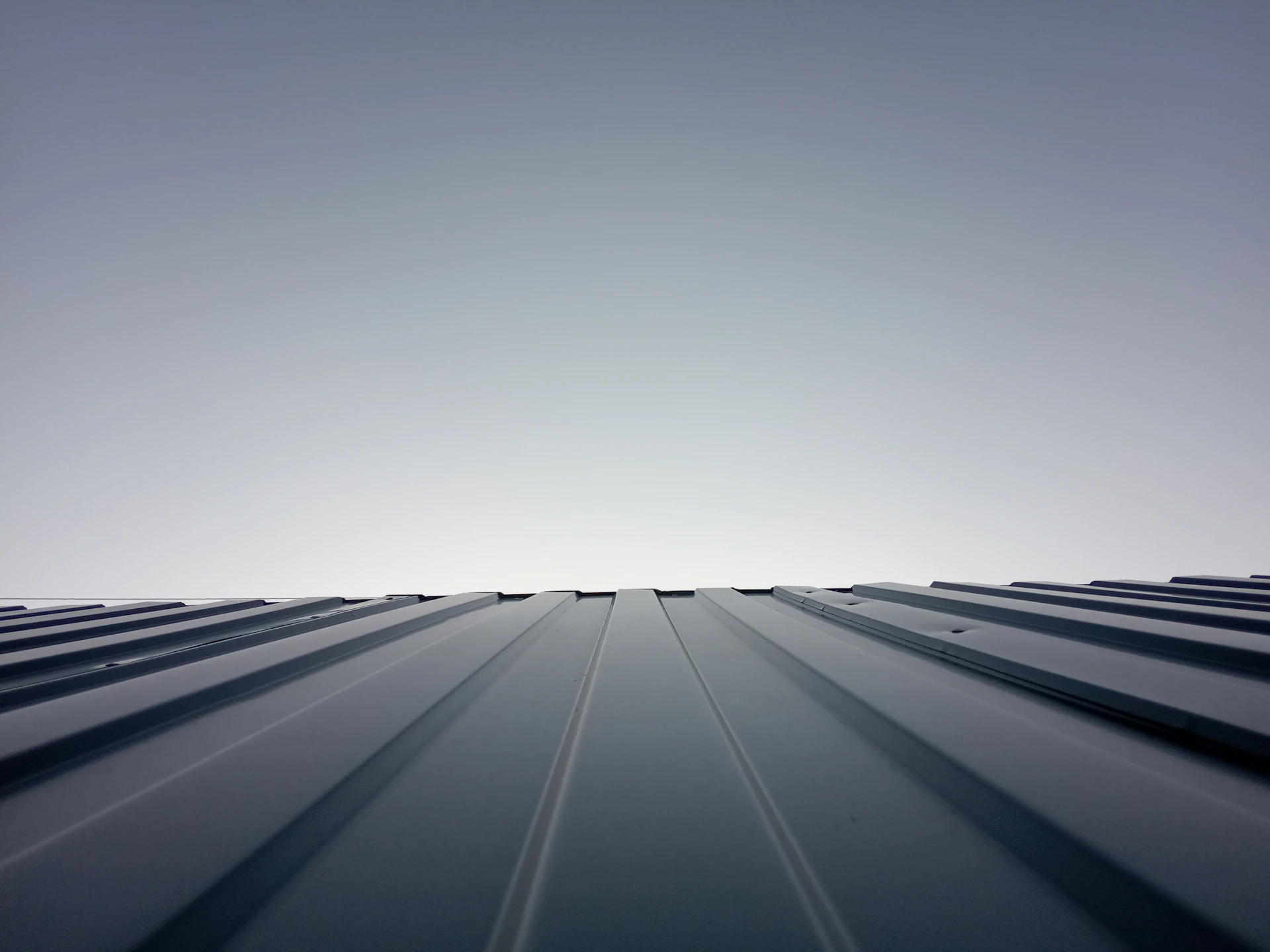 A freshly completed roofing project showcasing clean lines and premium materials under a bright blue sky.