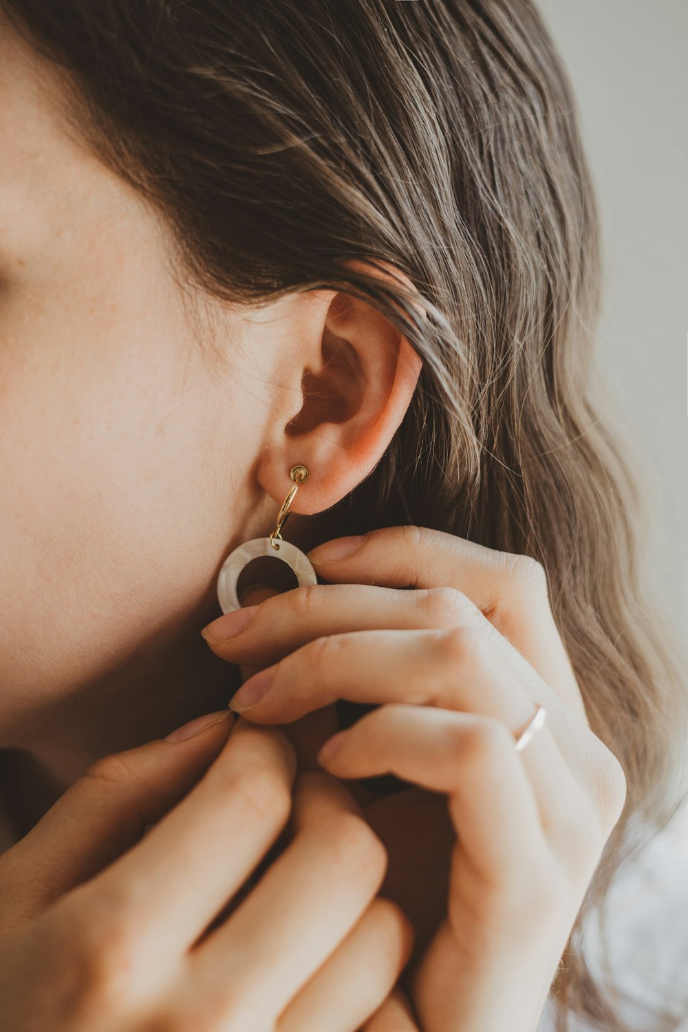 Woman holding earing in fingers.