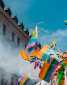 A vibrant crowd waving flags during an Independence Day parade under a clear blue sky.