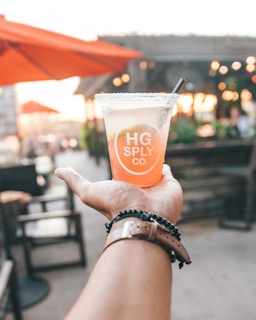 A person enjoying a drink from a vibrant tumbler outdoors.