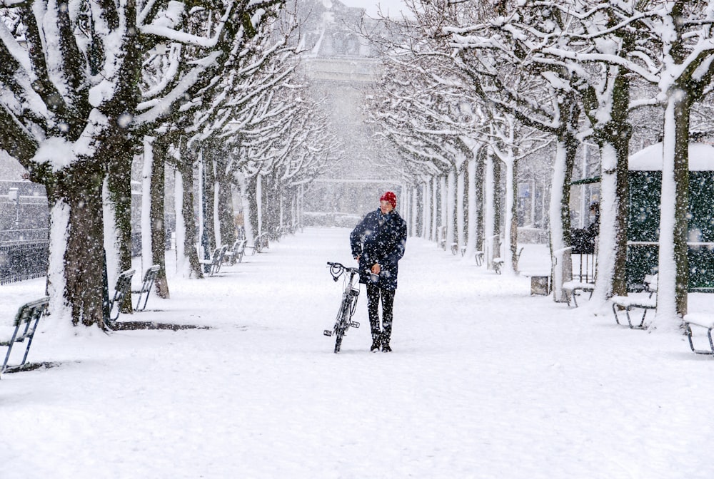 man walking with his bicycle during snow