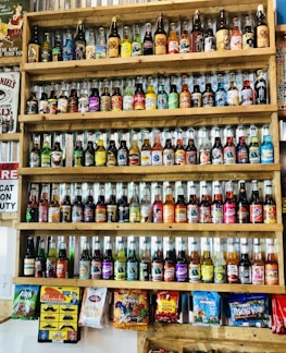 A vibrant display of assorted colorful soft drinks bottles on a wooden shelf.