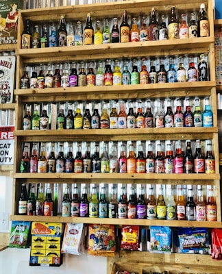 A vibrant display of assorted colorful soft drink bottles on a wooden shelf.