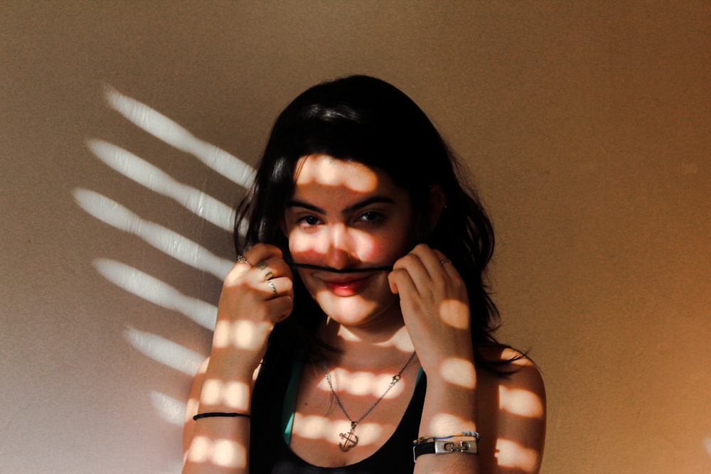 woman in black tank top beside wall