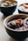 A bowl filled with a dark liquid, containing visible black tapioca pearls and chunks of sweet potato. Another bowl with similar contents is visible in the background.