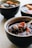 A bowl filled with a dark liquid, containing visible black tapioca pearls and chunks of sweet potato. Another bowl with similar contents is visible in the background.