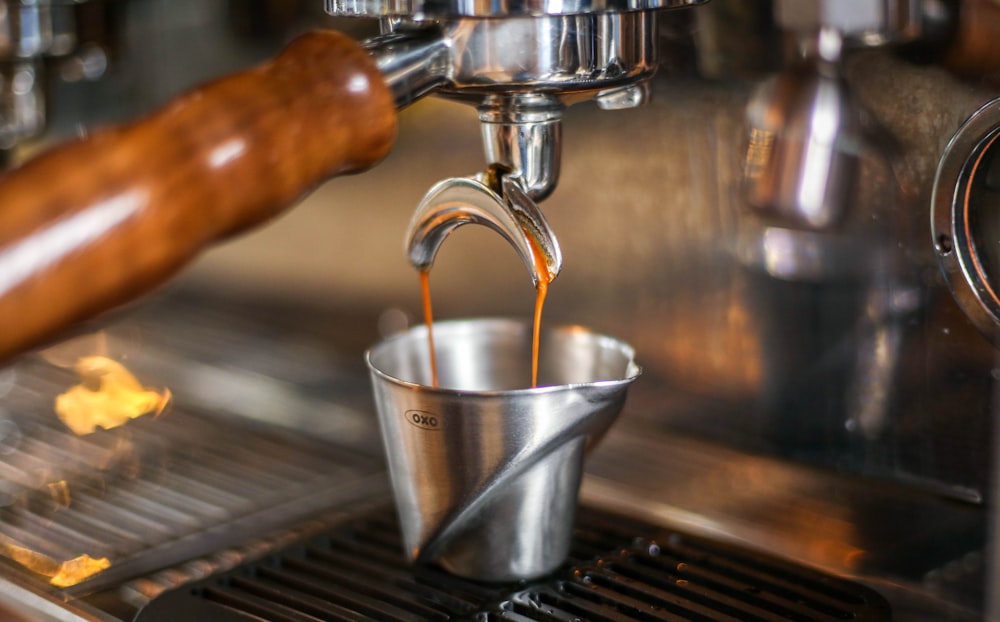 closeup photo of machine pouring beverage in metal bucket