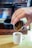 A man carefully pouring espresso into a glass with coffee equipment in the background.
