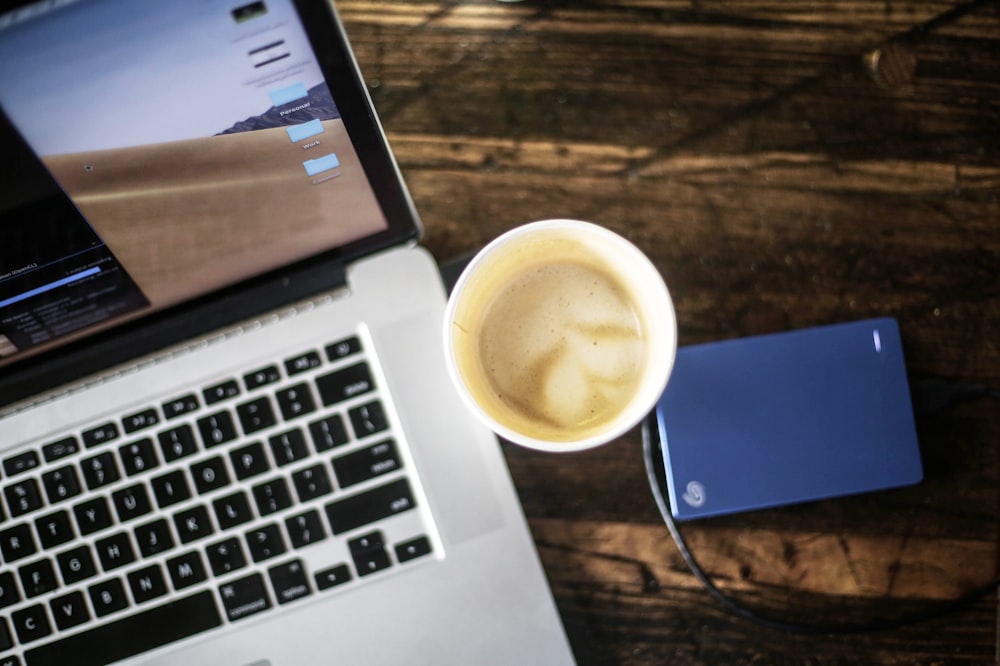 cup of coffee latte between turned-on laptop and Seagate portable drive