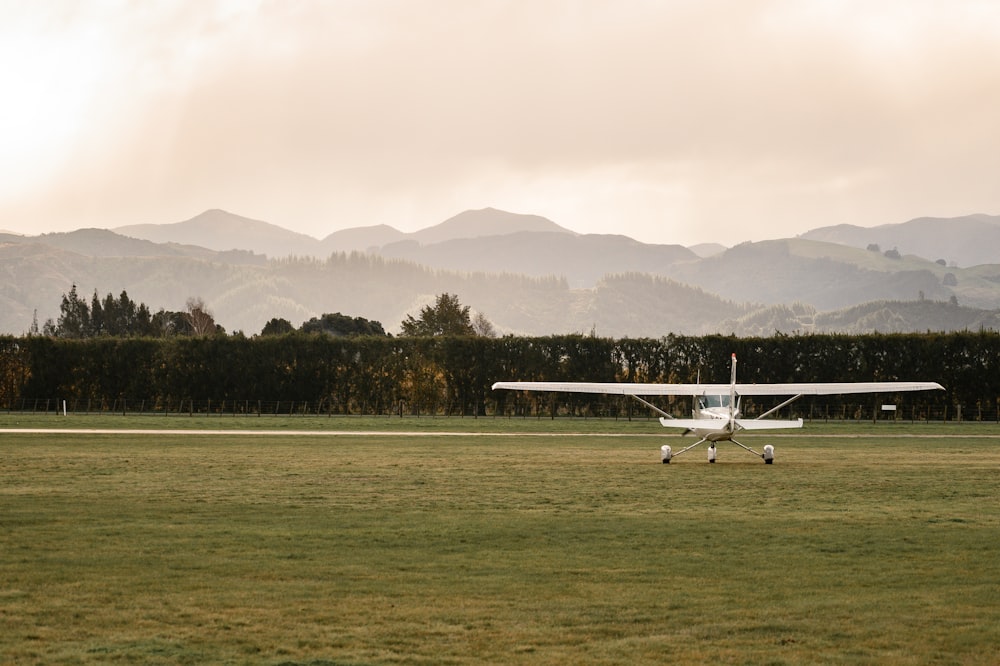 white plane on green field under cloudy sky