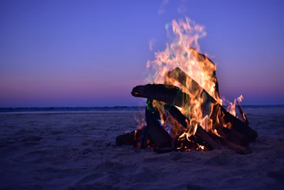 A beach bonfire glowing warmly as evening falls.