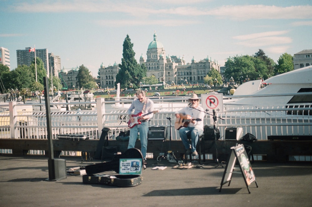 two men playing guitars on street