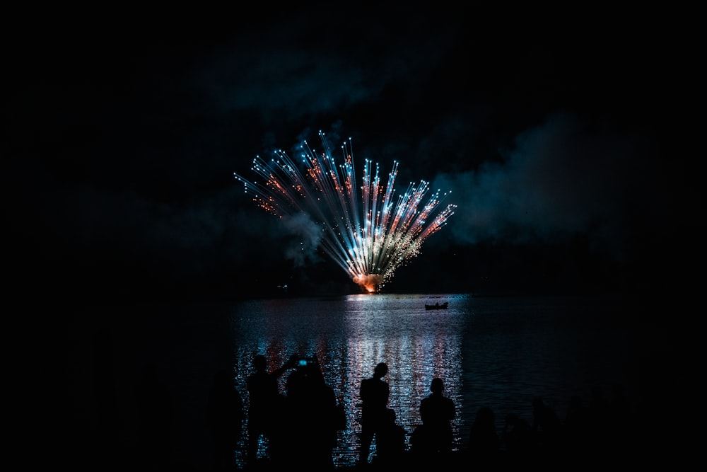 a group of people watching fireworks on the water