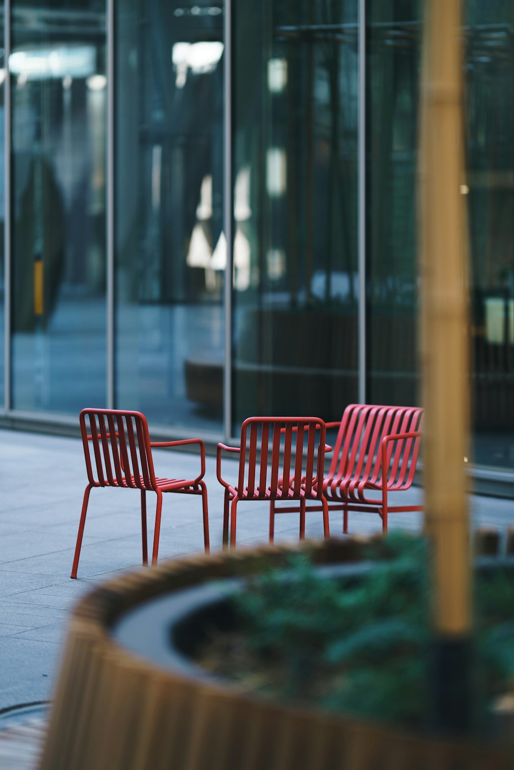 three red metal armchairs outside glass wall