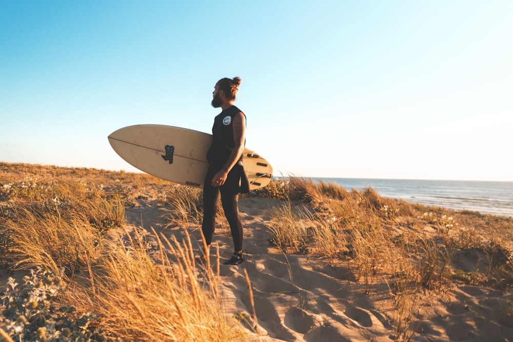 man carrying surfboard standing on shore