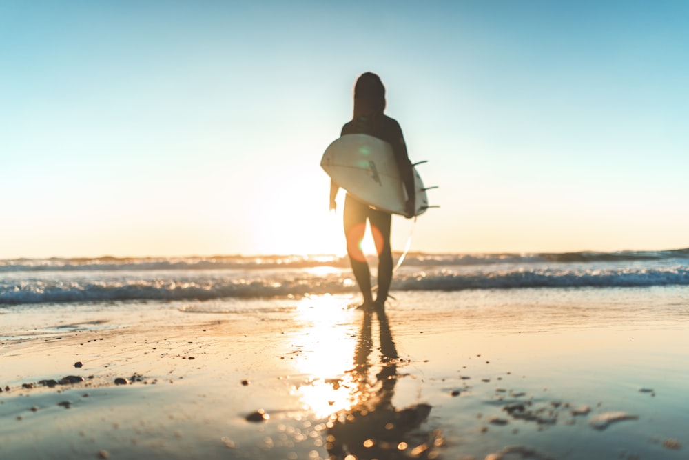 woman carrying white surfboard