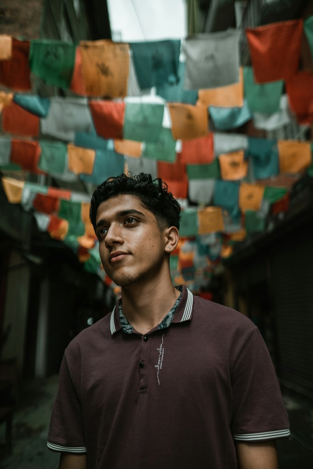 man in brown polo shirt standing in between houses