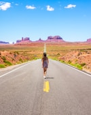 woman in black and grey dress walking in middle of highway