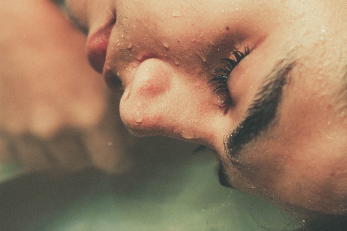 A close-up of a face with water droplets scattered across the skin