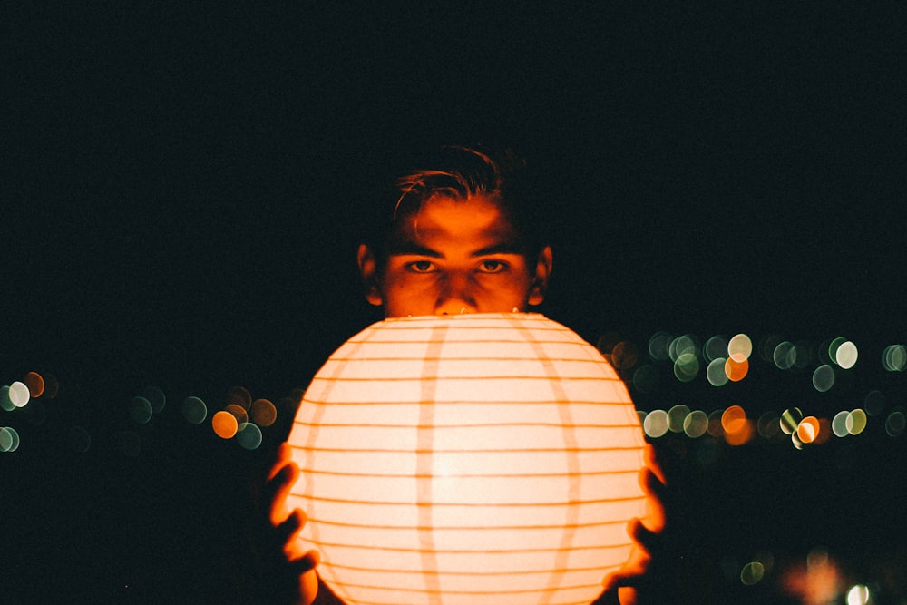 close-up photography of man holding lantern during nighttime
