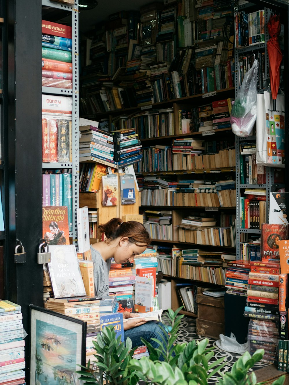 woman reading book in between books in shelf