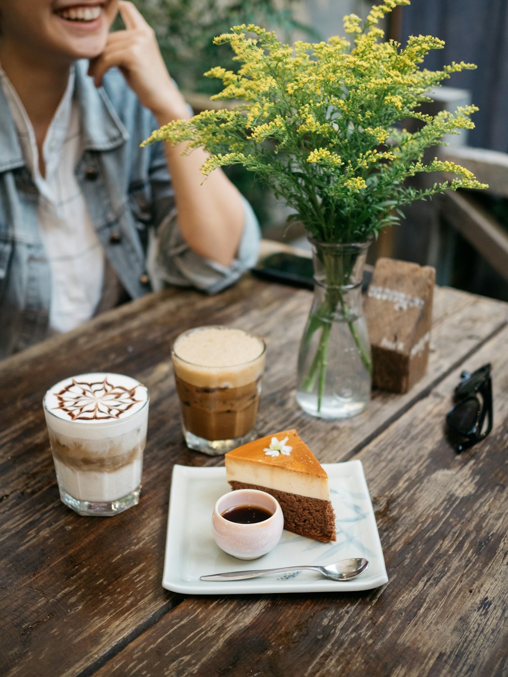 sliced cake near cappuccino and gray stainless steel teaspoon in plate on table