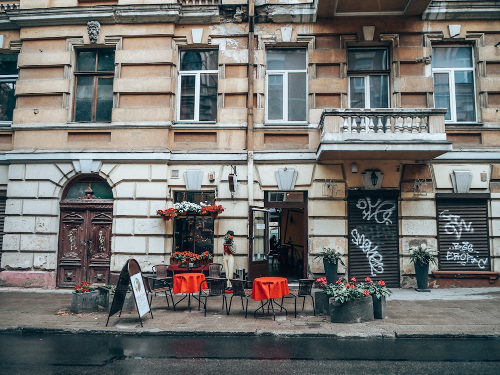 empty tables and chairs beside folding sign near road during daytime