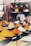 A variety of colorful spices are displayed in conical piles on a market stall, each labeled with small black signs. In the background, large jars filled with different substances are neatly arranged on shelves.