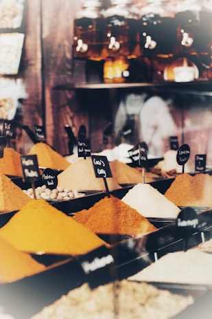 Colorful spices and herbs in small glass jars lined up on a market counter.