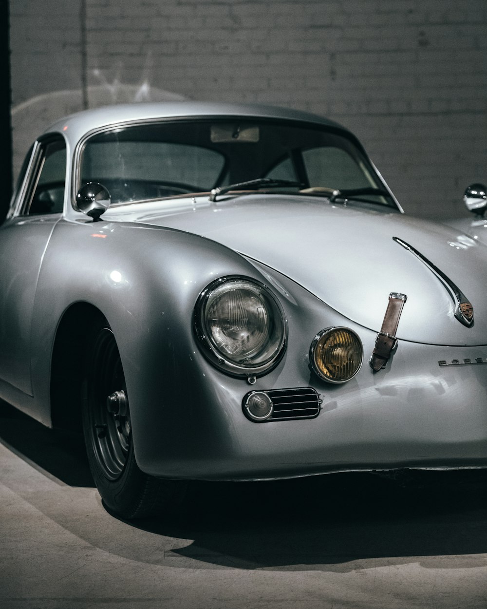 silver coupe parked near wall