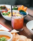 A refreshing glass of fresh lemonade with condensation beads, sitting beside a garden fresh salad.