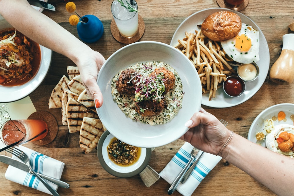 person holding white plate with food