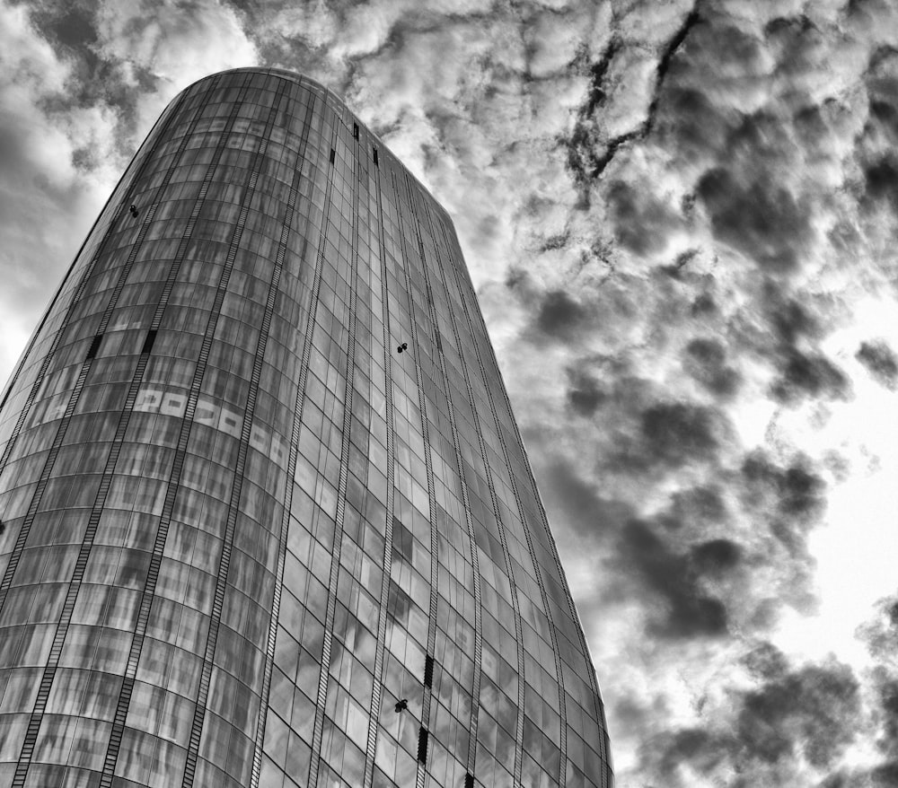 a very tall glass building under a cloudy sky