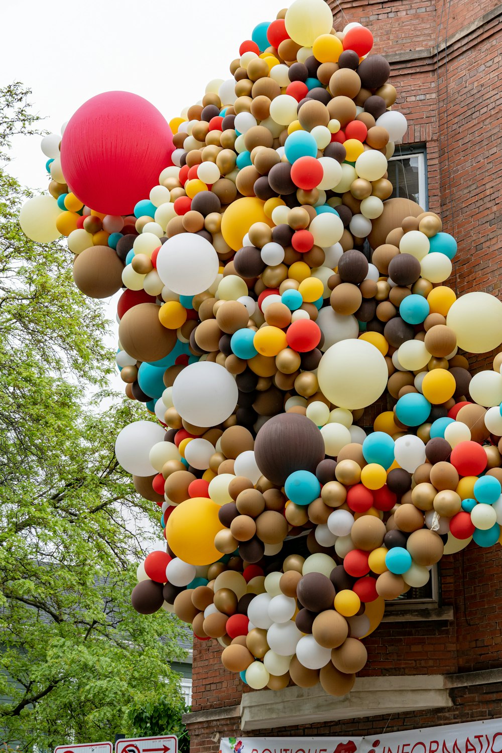 Lote de globos en un edificio marrón cerca de un árbol durante el día