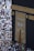 A large gathering of people surrounds the Kaaba, a sacred Islamic structure covered with an ornate black and gold cloth featuring Arabic calligraphy. People are dressed mostly in white robes, which is traditional attire for pilgrims.