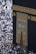 A large gathering of people surrounds the Kaaba, a sacred Islamic structure covered with an ornate black and gold cloth featuring Arabic calligraphy. People are dressed mostly in white robes, which is traditional attire for pilgrims.