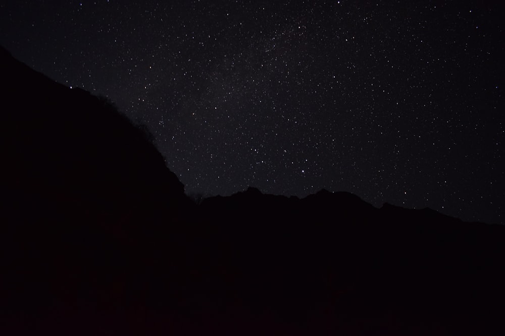 the night sky with stars above a mountain