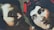 A large mural depicts two human faces with expressive features. The artwork is painted on a corrugated metal surface, creating a textured appearance. The faces are drawn in a dramatic and classical style, one with a serious expression and the other with wide-open eyes.
