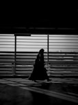 grayscale photo of woman walking near window