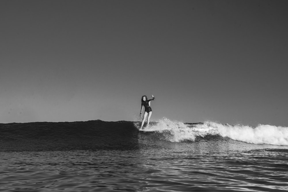 grayscale photo of woman surfboarding