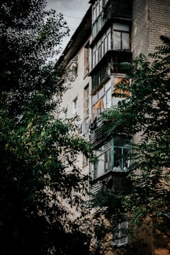 Exterior view of a multi-family brick building with balconies and greenery.
