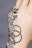 Intricate black henna patterns are delicately designed on the back of a hand. The design features floral motifs, circular patterns, and dotted lines, creating an elegant and artistic effect.