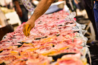Close-up of a vendor carefully selecting fresh fish at a bustling market stall.