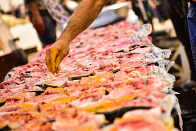 Close-up of hands selecting fresh fish and shellfish at a wholesale seafood stall.