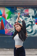 Side profile of a confident model in a sleek jacket, with graffiti art blurred in the background.